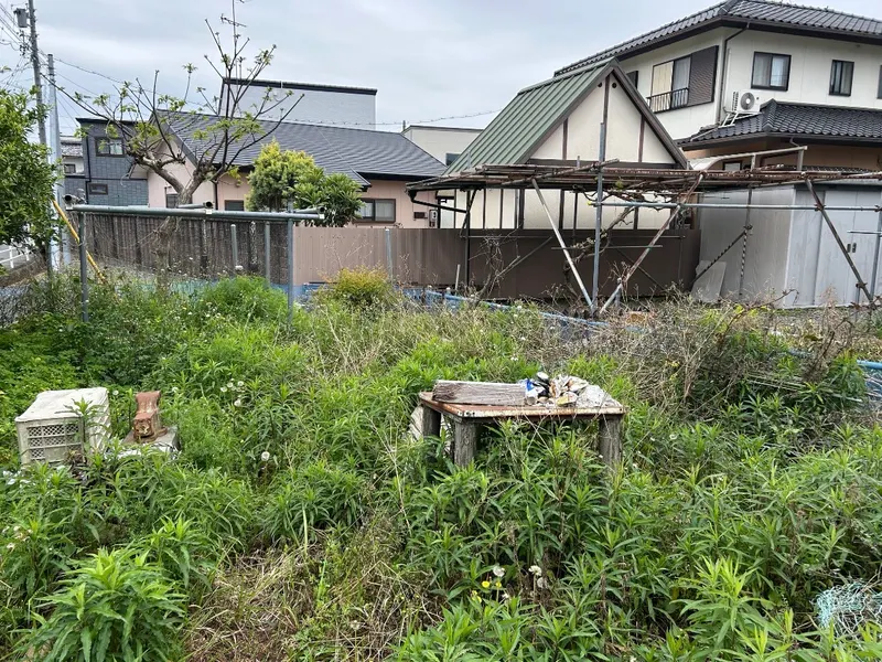 浜松市で空き地の草刈りを行う前、雑草が生い茂り不用品が放置された様子